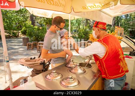 Antalya, Turkey - 4.09.2020: Seller give Traditional turkish ice cream to man with baby girl in a summer day in Antalya, Turkey Stock Photo
