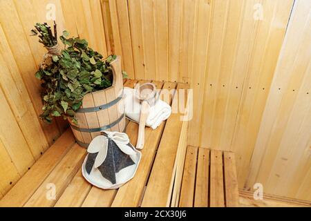 Interior details Finnish sauna steam room with traditional sauna accessories basin birch broom scoop felt hat towel. Traditional old Russian bathhouse SPA Concept. Relax country village bath concept Stock Photo