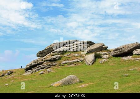 Haytor Rock in Dartmoor National Park, with a bright blue cloudy sky and lush green grass foreground.  A popular place for tourists and hikers Stock Photo