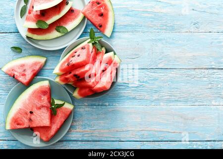 Fresh red sliced ripe watermelon with mint on a blue plates. Top view witn copy space. Summer concept. Stock Photo