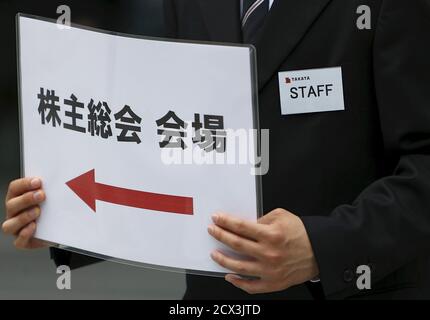 An Employee Of Japanese Auto Parts Maker Takata Corp Holds A Signboard Of The Company S Annual
