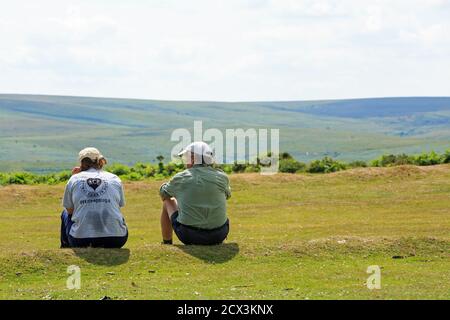 Two Walkers take a rest on the lush green grass in Dartmoor National Park, Devon Stock Photo