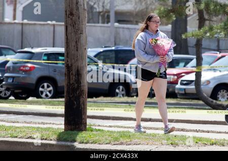 A girl walks with flowers in front of Jonathan Law High School in Milford, Connecticut April 25, 2014. A 16-year-old girl was killed on Friday in an attack inside a Connecticut high school and authorities were investigating reports she was stabbed by a fellow student after rejecting his invitation to the prom, police said. The victim, Maren Sanchez, a junior at Jonathan Law High School in Milford, was pronounced dead at the hospital shortly after the 7 a.m. (1100 GMT) attack, Milford Police Chief Keith Mello told a news conference. REUTERS/Michelle McLoughlin (UNITED STATES - Tags: EDUCATION C