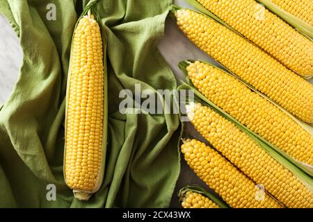 Fresh corn on cobs on table with green towel. Top view. Stock Photo