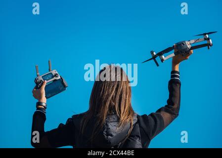 A back side view of young woman in black jacket holding drone before the flight Stock Photo