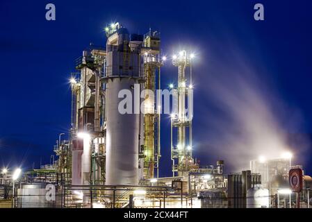 Oil refinery after sunset with lights and steam Stock Photo