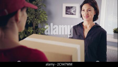 Brunette looking deliveryman holding box Stock Photo