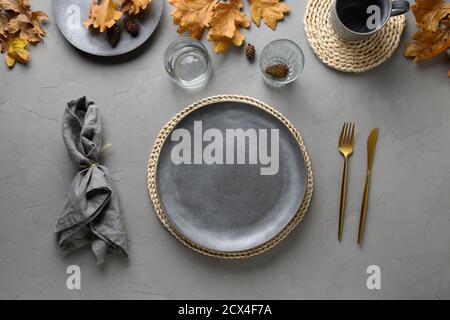 Autumn festive table setting with fall golden decor and empty plate for design on grey table. Flat lay, top view. Stock Photo