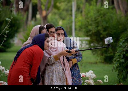 Modern Iranian women taking a group selfie, Hasht Behest Palace gardens, Isfahan, Iran Stock Photo