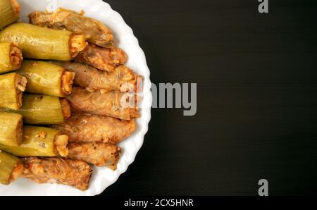 Traditional stuffed squash and cabbage rolls on white plate on dark wooden background with copy space. Famous traditional Middle East, Egyptian, Asian Stock Photo