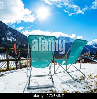 Pair of deck chairs near ski with mountains and Alpine peaks panorama on background Stock Photo