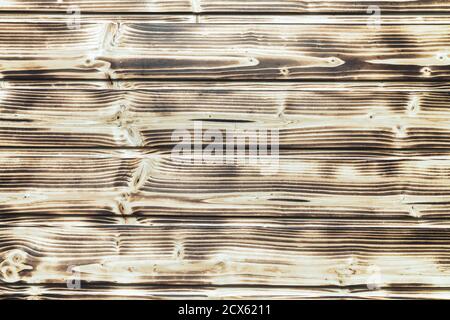 Old burnt wooden plank brown decorative background with horizontal boards. Flat lay close-up view. Stock Photo