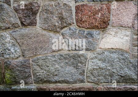 Background of the wall of granite textured stones cemented together, horizontal view Stock Photo