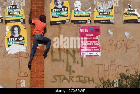 A child climbs past defaced election posters during an election rally of President Jacob Zuma's African National Congress (ANC) in Bekkersdal township south of Johannesburg, May 3, 2014. South Africa goes to the polls on May 7 in  elections which are expected to keep the ANC in power. REUTERS/Mike Hutchings (SOUTH AFRICA - Tags: POLITICS ELECTIONS TPX IMAGES OF THE DAY)