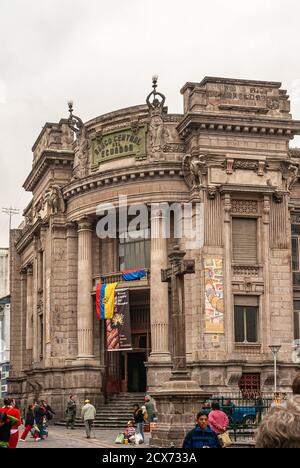 Quito, Ecuador - December 2, 2008: Historic downtown. Street corner with historic National Bank building and entrance, with giant cross statue in fron Stock Photo