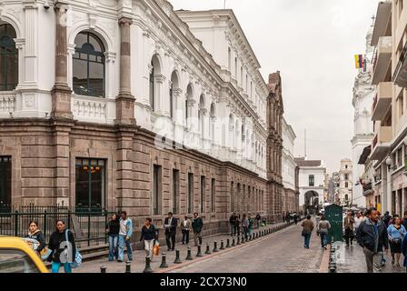 Quito, Ecuador - December 2, 2008: Historic downtown. Street scene with pedestrains in front of white and brown stone Metropolitan Cultural Museum in Stock Photo