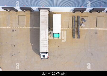 Aerial view of goods warehouse. Logistics center in industrial city zone from above. Aerial view of trucks loading at logistic center. View from drone Stock Photo