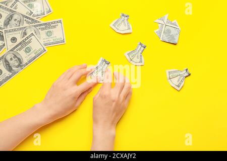 Woman making origami figures from dollar banknotes on color background Stock Photo