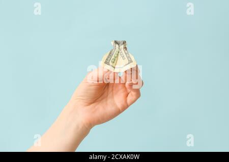Female hand with origami dress made of dollar banknote on color background Stock Photo