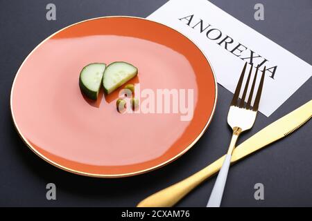 Plate with vegetables and cutlery on dark background. Concept of anorexia Stock Photo