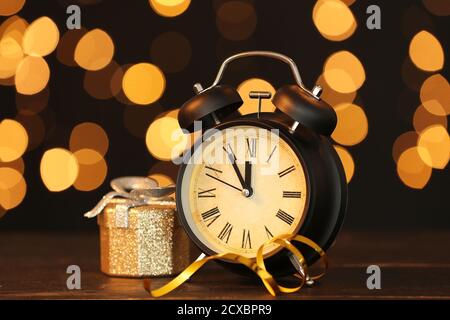 Alarm clock and Christmas gift against blurred lights Stock Photo