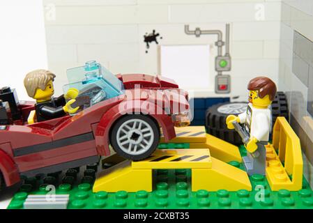 Florianopolis, Brazil. September 19, 2020: Grease dirty mechanic minifigure looking at car entering his auto repair garage for repair and maintenance. Stock Photo