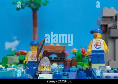 Florianopolis, Brazil. September 20, 2020: Happy man minifigure watching his son catch a shark with a fishing rod. Funny scene. Family leisure concept Stock Photo
