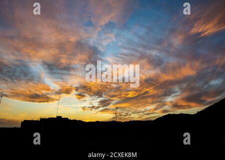 a image of golden clouds on a rainbow blue background during a sunset with cityscape silhouette Stock Photo