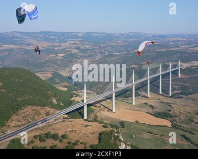 AIR-TO-AIR VIEW. Paramotors flying in the vicinity of the Millau Viaduct, the world's tallest bridge as of 2020. Millau, Tarn Valley, Aveyron, France Stock Photo