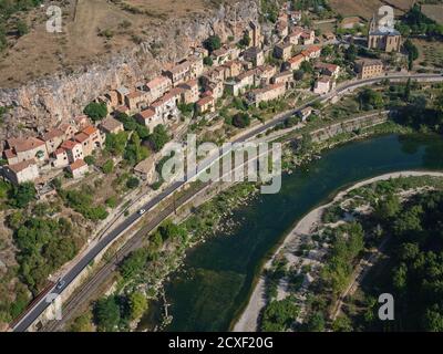 AERIAL VIEW. Picturesque village situated at the foot of a cliff and overlooking the Tarn River. Peyre, Comprégnac, Aveyron, Occitanie, France. Stock Photo
