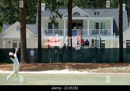 Spectators watch from a private home along the third fairway as Hideki Matsuyama of Japan hits his approach shot during the third round of the U.S. Open Championship golf tournament in Pinehurst, North Carolina, June 14, 2014. REUTERS/Mike Segar (UNITED STATES - Tags: SPORT GOLF)