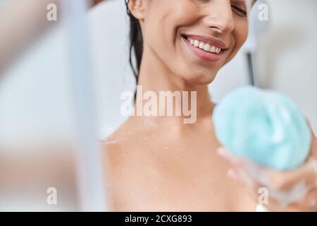 Cheerful young woman holding bath loofah sponge Stock Photo