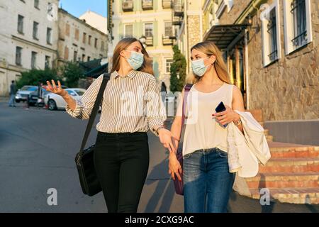 Office workers two women walking, wearing medical protective masks Stock Photo