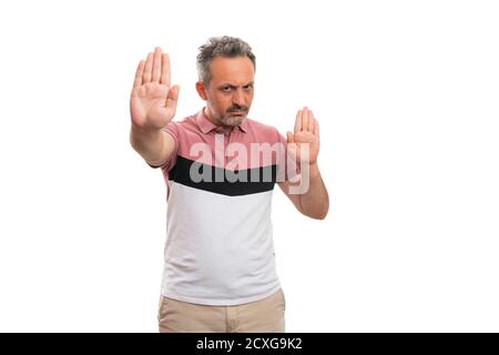 Angry male model with serious annoyed expression making stop stay away gesture using both hands palms wearing casual summer attire isolated on white b Stock Photo