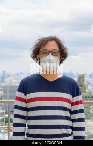 Portrait of Japanese man wearing mask against view of the city Stock Photo