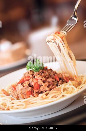 Swirl of spaghetti with minced meat and red chili flakes on a fork Stock Photo