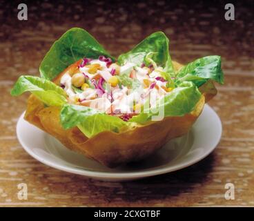 Green salad with fresh vegetables in waffle bowl on the table Stock Photo