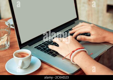 A girl works at laptop in a cafe placed on wooden table. Stock Photo