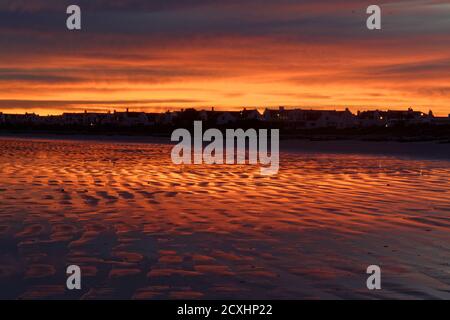 Early dawn before sunrise giving wonderful red/orange color to sky and beach. Paternoster beach in the Western Cape, South Africa Stock Photo