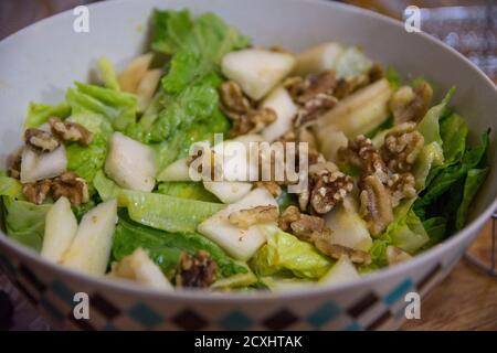 Lettuce salad with Persian walnuts, and slices of apples, served in a bowl Stock Photo