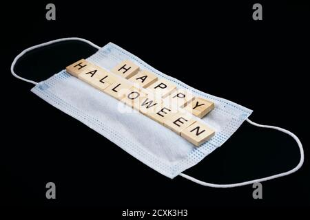 Medical mask and wooden words Happy Halloween on black. Halloween background decor holiday concept Stock Photo