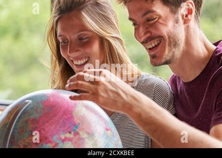 Young couple exploring world globe while sitting in living room Stock Photo
