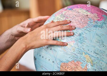 Couple's hands exploring world globe Stock Photo