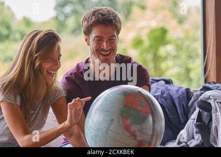 Young couple exploring world globe while sitting on sofa Stock Photo