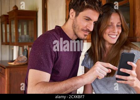 Young couple using smartphone in kitchen Stock Photo