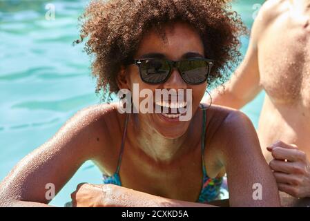 Laughing young woman leaning at poolside Stock Photo