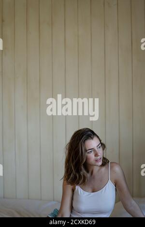 Beautiful young woman sitting on bed Stock Photo