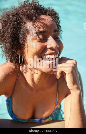 Laughing young woman leaning at poolside Stock Photo
