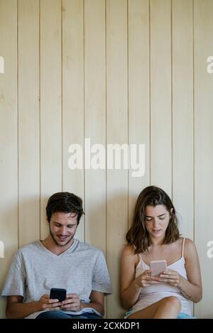 Young couple using smartphones in bedroom Stock Photo