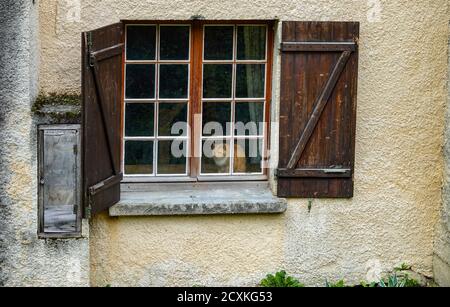 Ginger and white cat looking out of window with shutters, Ariege, French Pyrenees Stock Photo